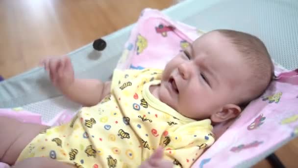 Recém-nascido travesso em uma cadeira de balanço do bebê — Vídeo de Stock
