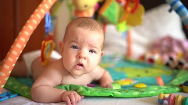 Немовля лежить на животі на ігровому килимку — стокове відео