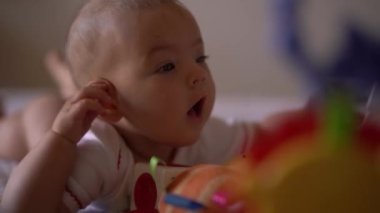 Bebek yatağa uzanıp ellerini sıvazlıyor ve ağzını açıyor.