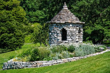 New York 'un kuzeyindeki Mohonk Dağ Evi' nin bahçesinde çiçek bahçesi ve taş duvarlı küçük taştan bir çardak..