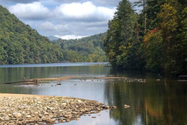 Doğanın sonbahar renkleri ağaçlarda, gölde yansımalar, mavi gökyüzü.