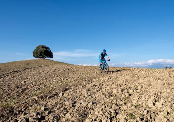 Ciclista de montaña a caballo a través del paisaje toscano — Foto de Stock