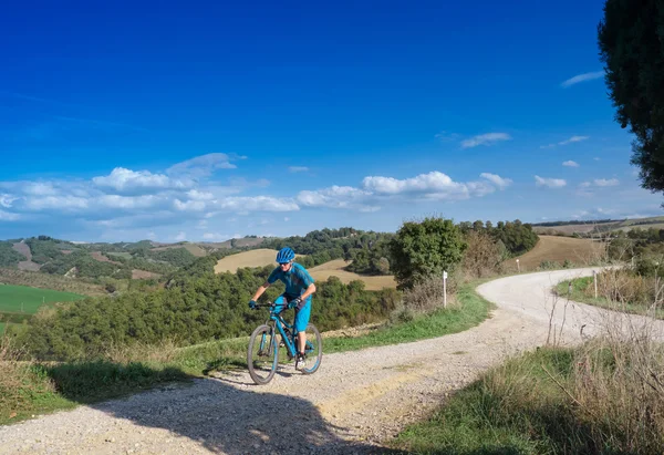 Ciclista de montaña a caballo a través del paisaje toscano — Foto de Stock