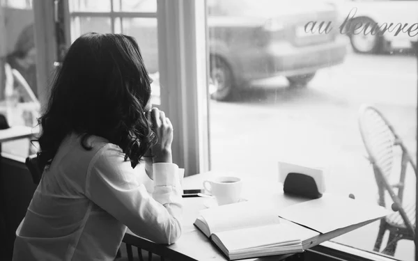 Wanita duduk di kafe dengan secangkir kopi, teh. Baca buku dan mimpi. Lihat ke luar jendela. Tunggu seseorang . — Stok Foto