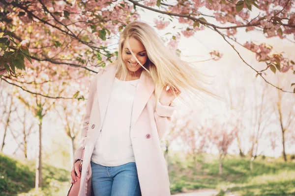 Młoda kobieta piękny różowy płaszcz pozowanie z kwiatami w gar — Zdjęcie stockowe