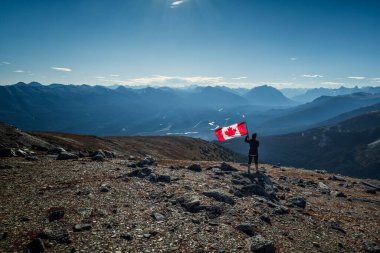 Kanada Rocky Dağları 'nda (Rocky Dağları) Kanada bayrağı taşıyan kadın Jasper Ulusal Parkı, Alberta, Kanada.