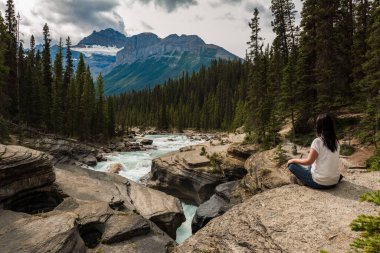 Jasper Ulusal Parkı, Alberta, Kanada 'da Mistaya Kanyonu' nda kayaların üzerinde oturmuş dinlenen bir kadın..