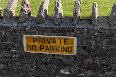 Özel bir konutun dışındaki taş bir duvara asılmış park yasağı levhası yakın çekim görüntüsü. 