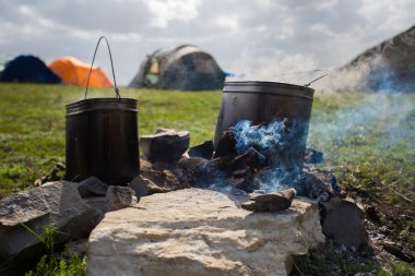 Bir kamp ateşi üzerinde dumanı tüten tencere