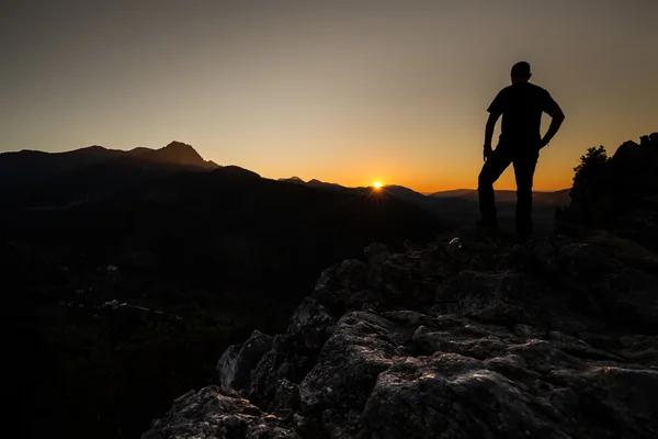 Turista na vrcholu hory při západu slunce. Žena, obdivovat horu pozemky — Stock fotografie