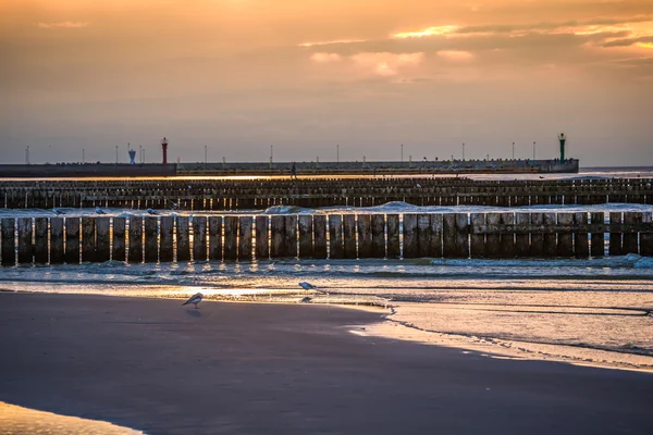 Tramonto sulla spiaggia con frangiflutti in legno a Leba, Mar Baltico, Po — Foto Stock