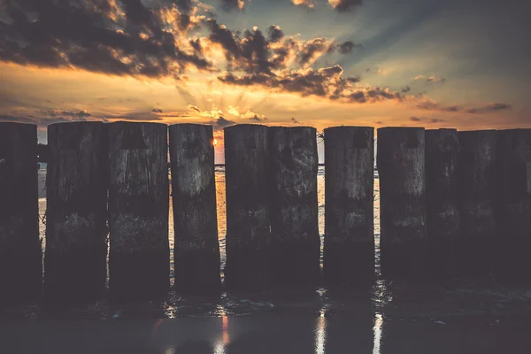 Puesta de sol en la playa con un rompeolas de madera en Leba, Mar Báltico, Po — Foto de Stock