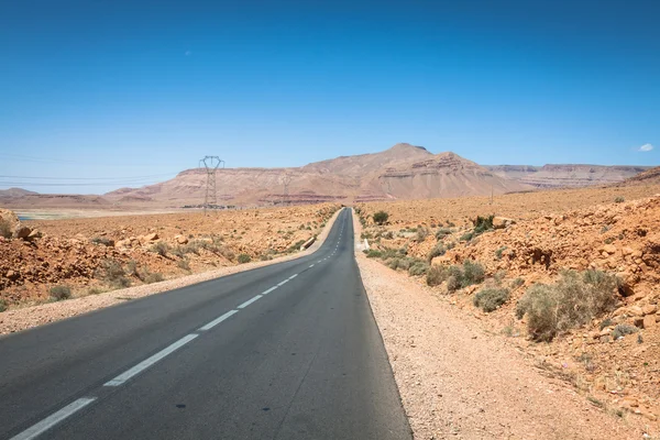 Nekonečné silnice v poušti Sahara s modrou oblohu, Maroko Afrika — Stock fotografie