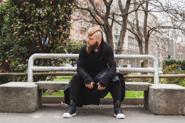 Bir bankta oturan şık sakallı adam