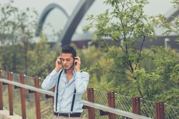 Giovane bell'uomo che ascolta musica in un contesto urbano — Foto Stock