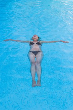 Sırtında bir yüzme havuzunda yüzen kadın