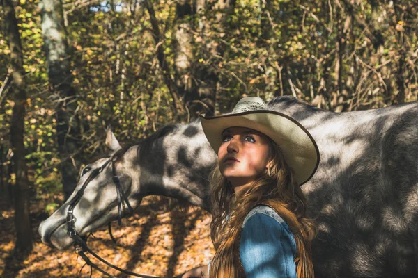 Pretty girl standing by her grey horse — Stock Photo, Image