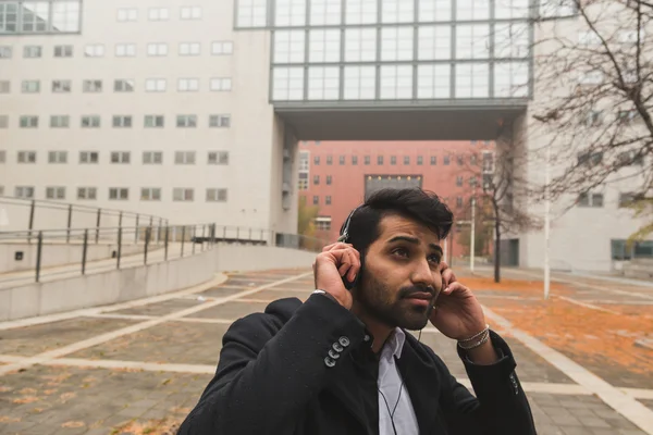 Hombre indio guapo escuchando música en un contexto urbano — Foto de Stock