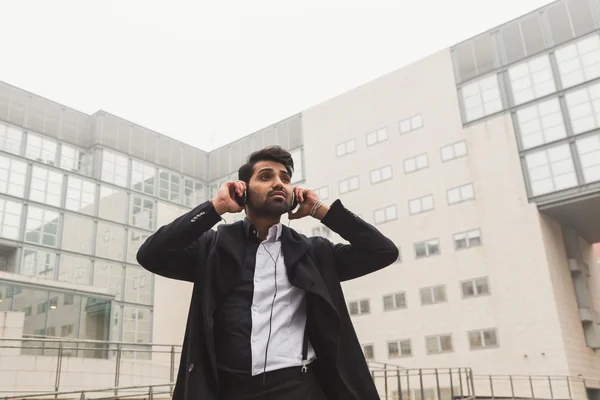 Hombre indio guapo escuchando música en un contexto urbano — Foto de Stock