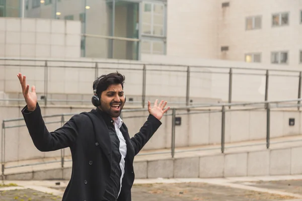 Красивый индийский мужчина слушает музыку в городском контексте — стоковое фото