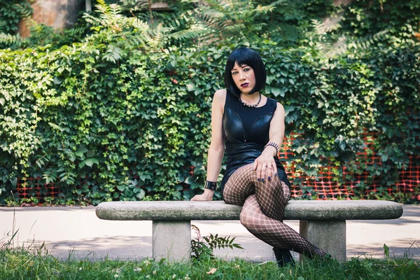 Pretty goth girl sitting in a city park — Stock Photo, Image