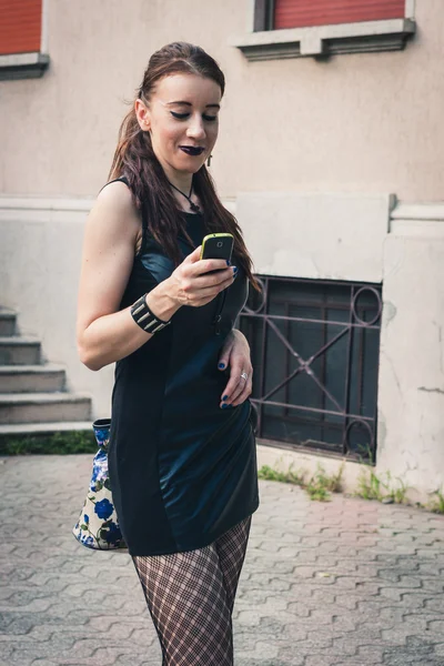 Pretty goth girl using phone in a city park — Stock Photo, Image