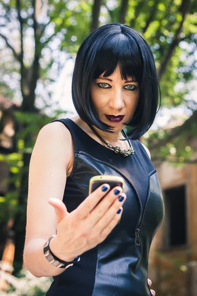 Söt goth flicka med telefonen i en park — Stockfoto
