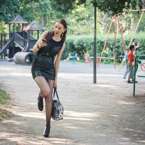 Mooi goth meisje met behulp van telefoon in een stadspark — Stockfoto