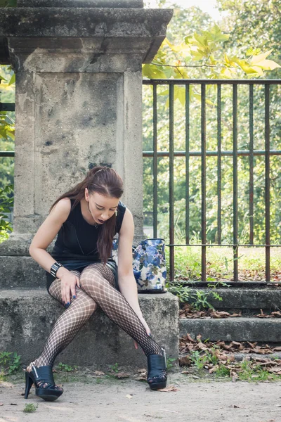 Mooie goth meisje zit in een stadspark — Stockfoto