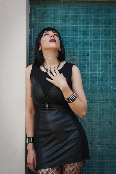 Pretty goth girl posing against a blue wall — Stock Photo, Image