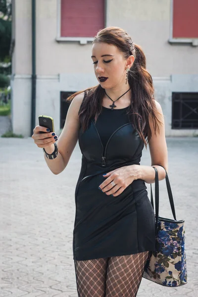 Pretty goth girl using phone in a city park — Stock Photo, Image