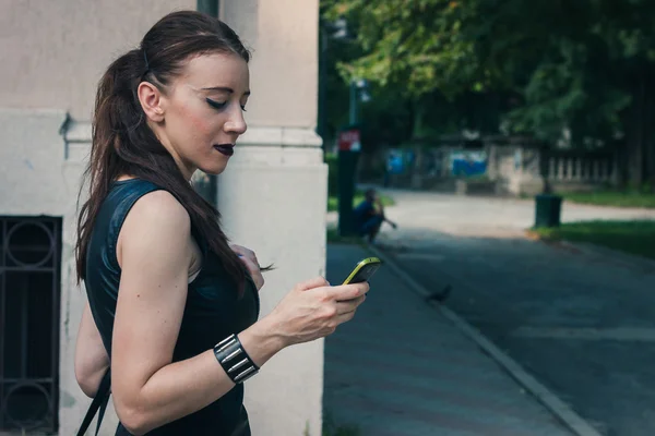 Chica bastante gótica usando el teléfono en un parque de la ciudad —  Fotos de Stock