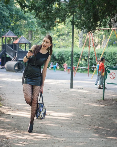 Hezká goth dívka použití telefonu v městském parku — Stock fotografie