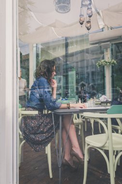 Bir pencere camdan çerçeveli restoranda oturan güzel kız