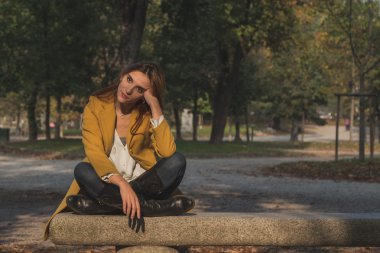 Kızıl saçlı kız bir şehir parkında poz