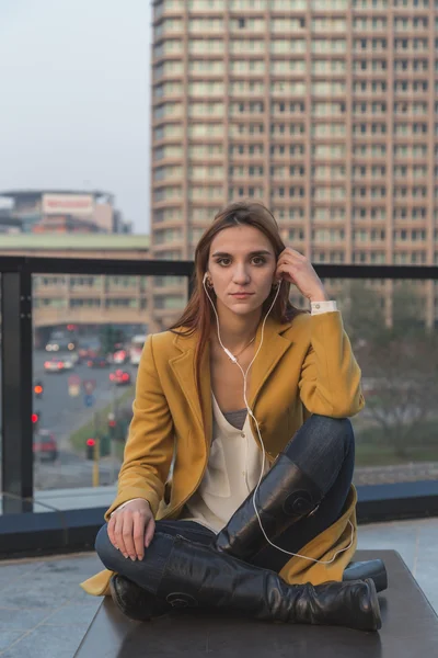 Rousse fille écoute de la musique dans les rues de la ville — Photo