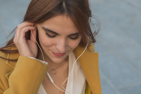 Ruiva menina ouvindo música nas ruas da cidade — Fotografia de Stock