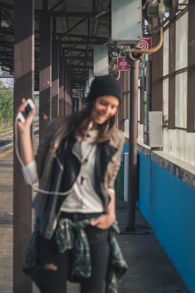 Intenzionalmente fuori fuoco bella ragazza che ascolta musica in una stazione della metropolitana — Foto Stock