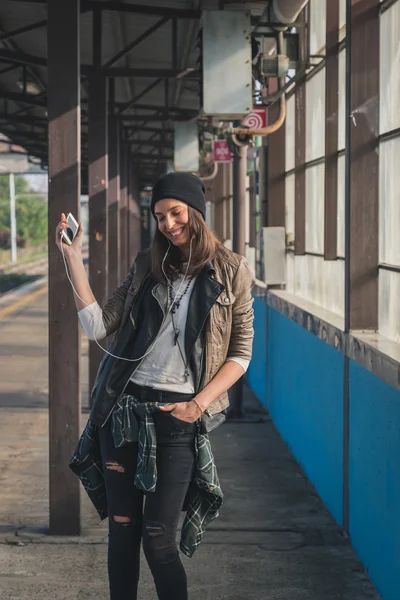 Chica bonita escuchando música en una estación de metro — Foto de Stock