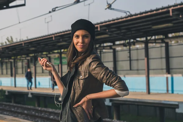 Pretty girl listening to music in a metro station — Stock Photo, Image