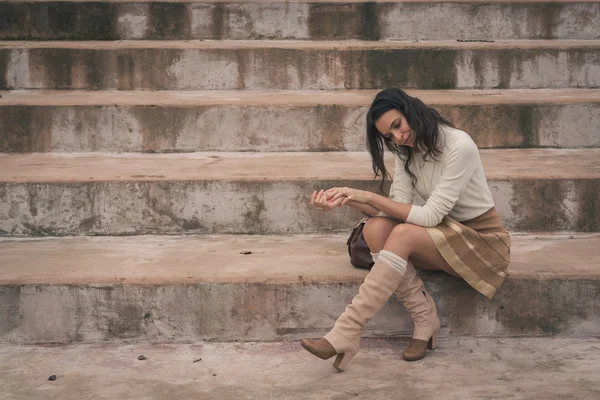 Beautiful young woman sitting on concrete steps — Stock Photo, Image