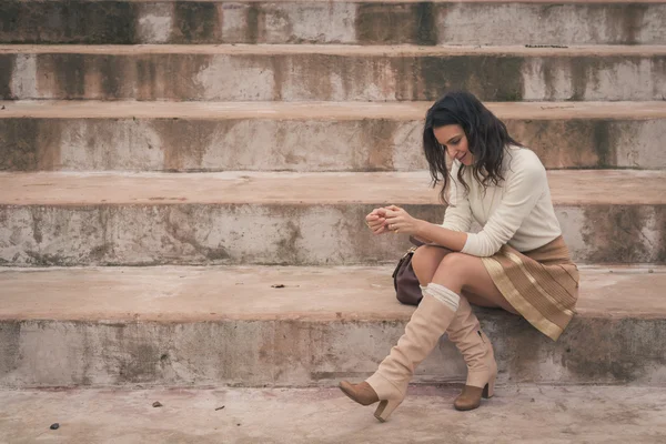 Krásná mladá žena sedící na konkrétních kroků — Stock fotografie