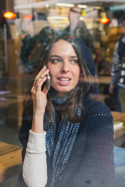 Beautiful girl talking on phone behind a window — Stock Photo, Image