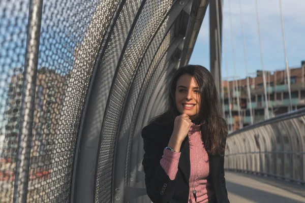 Mooie jonge brunette die zich voordeed op een brug — Stockfoto