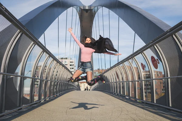 Bella giovane bruna che salta su un ponte — Foto Stock