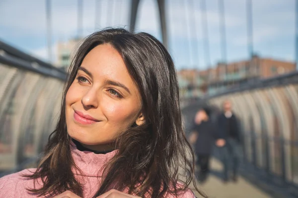 Beautiful young brunette posing on a bridge — Stock Photo, Image