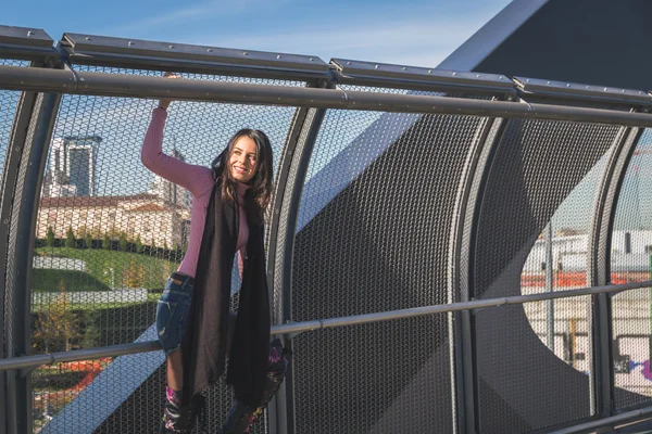 Beautiful young brunette posing on a bridge — Stock Photo, Image