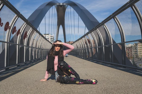 Beautiful young brunette posing on a bridge — Stock Photo, Image