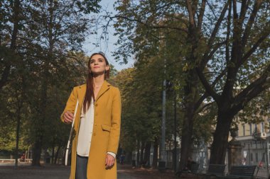 Kızıl saçlı kız bir şehir parkında poz