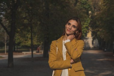 Kızıl saçlı kız bir şehir parkında poz